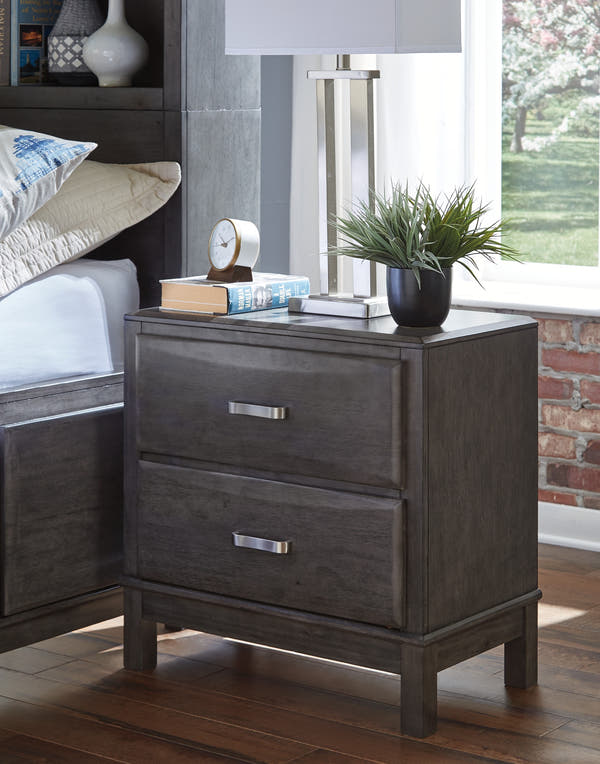 Caitbrook Gray Nightstand beside a bed