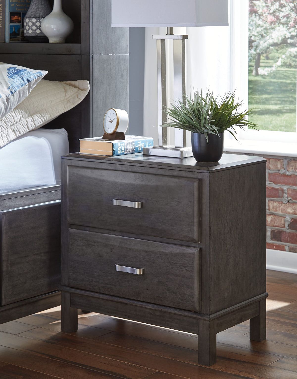 Caitbrook Gray Nightstand beside a bed