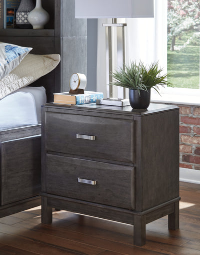 Caitbrook Gray Nightstand beside a bed