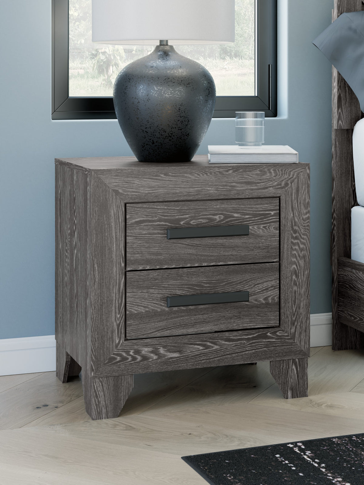Sylveri Warm Gray Two Drawer Nightstand beside a bed
