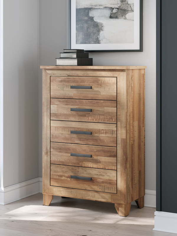 Finaria Warm Brown Five Drawer Chest in a bedroom