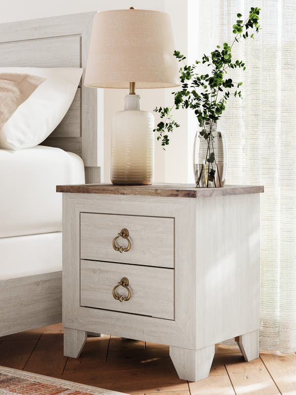 Laigmeyer Two-tone Two Drawer Nightstand beside a bed